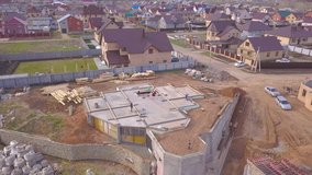Top view of concrete base of house. Clip. Workers at construction site check concrete base of house under construction on background of country cottages