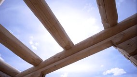 Close-up view of wooden structure of house. Clip. Building house of good wooden logs. Construction of wooden house on blue sky