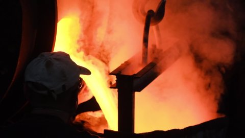 Hot steel pouring at steel plant. Stock footage. Flowing metal at the foundry. Pouring of liquid metal in open hearth workshop