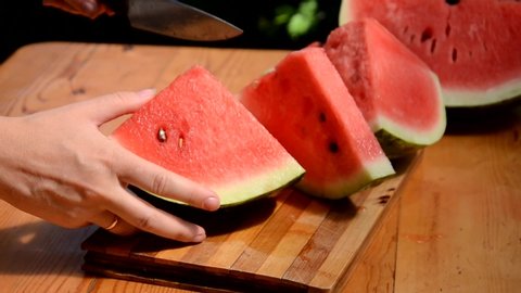 Three pieces of watermelon put on a chopping block. Chopper cutting a piece of water melon with knife. It is summer in Thailand. When everyone eats watermelons so delicious and fresh.
