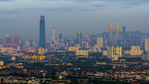 Time lapse: Foggy and dramatic first light sunrise view of Kuala skyline from afar and high angle in Malaysia at dawn.