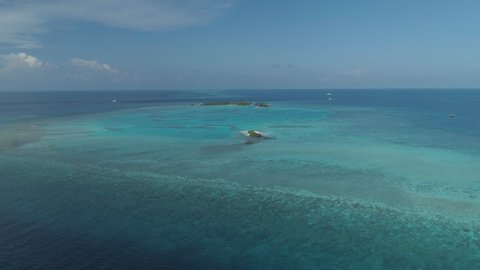 Glide shot towards tiny Maldives island in the beautiful clean Indian Oceans