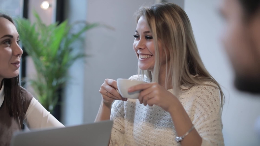 Two friends in a cafe are having fun chatting and smiling discussing work and business ideas with their friend. Funny company. | Shutterstock HD Video #1032379442