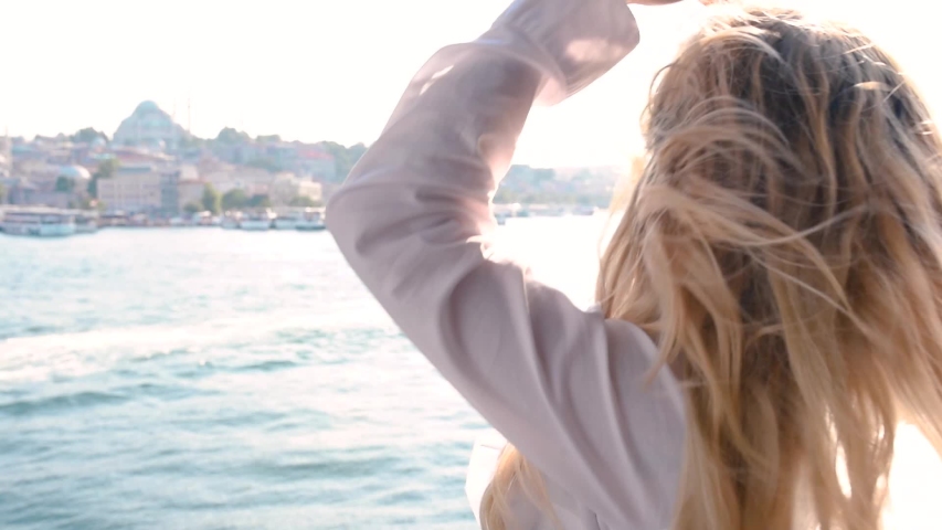 Beautiful girl poses over Galata Bridge and enjoys view of bosphorus and Suleymaniye Mosque in Istanbul,Turkey.