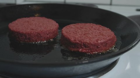 Vegan plant based burgers frying in skillet