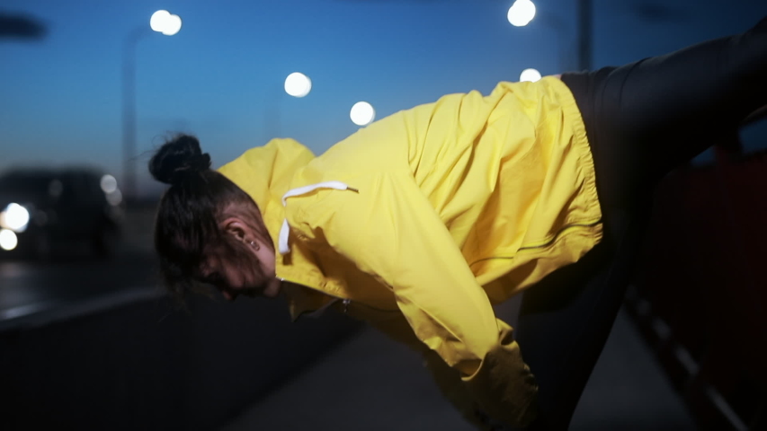 Sporty woman stretches her leg at night city