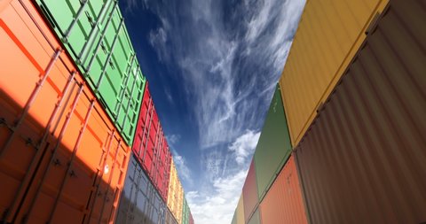 Cargo shipping container stacks under cloudscape. Industrial containers are excellent for cargo import export shipment. Camera seamlessly moves thru cargo boxes of different transportation companies