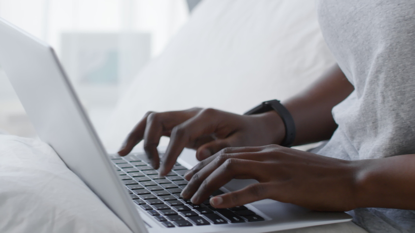 Close up shot of young black woman sitting in bed after waking up in the morning and using laptop computer for work | Shutterstock HD Video #1032395381