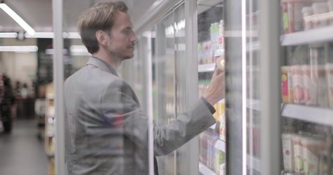 Adult male grocery shopping opening door to fridge