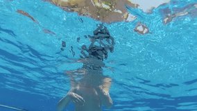 Closeup underwater portrait of cute funny white kid swimming in blue summer pool outdoor. Real time full hd video footage.