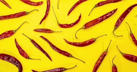 Red Chile de árbol chilies stop motionement as pattern on fun vibrant yellow background 4k