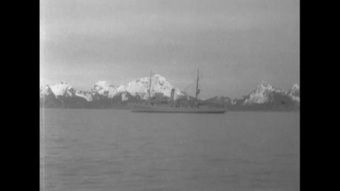 CIRCA 1932 - US Navy surveying vessels are seen sailing by snow-capped Alaskan mountains.