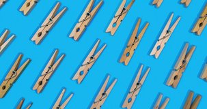 clothespins laid out in pattern opening and closing stop motion effect on vibrant blue background