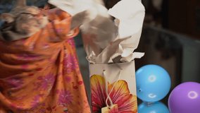 This video shows a cute cat opening a colorful package gift, excitedly taking out the tissue paper.