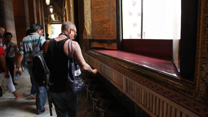 Bangkok, June 2013: Tourist dropping coins on bowls at Wat Pho Temple 
