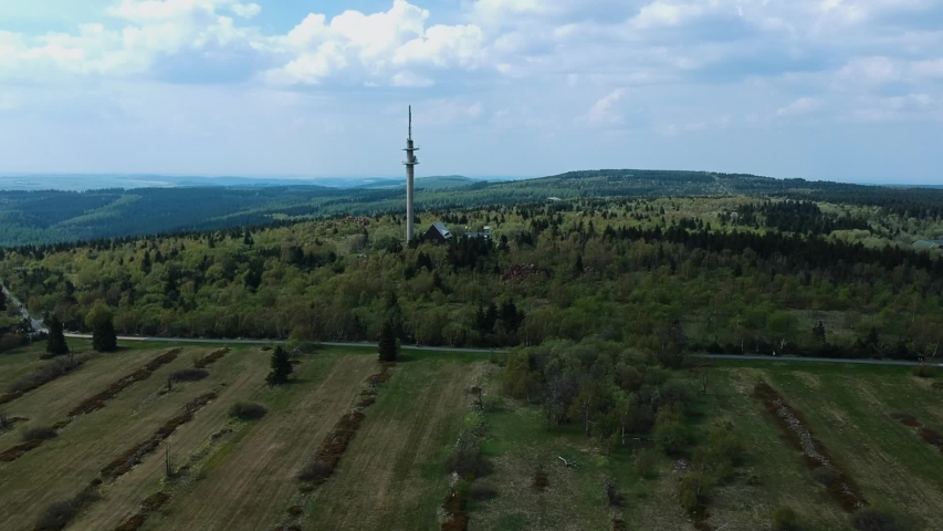 Drone flying up to show tall tower in the middle of the countryside