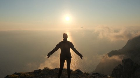 Silhuette Young Woman arms outstretched observing a beautiful dramatic sunset above a sea from a high mountain in Crimea. 스톡 비디오
