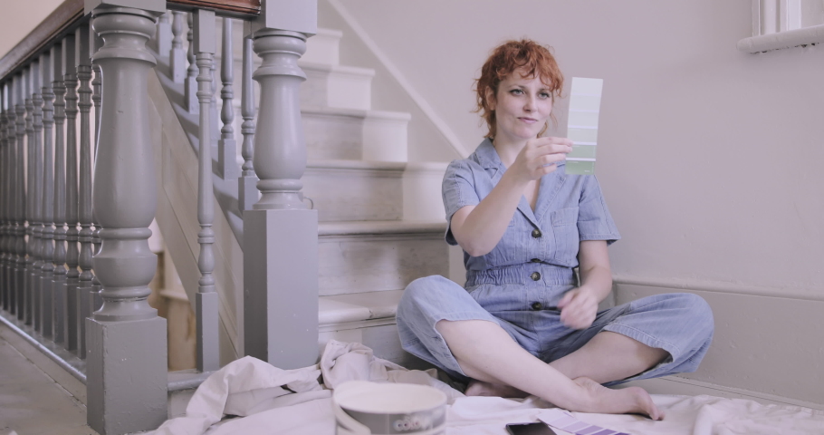 Adult woman in new home looking at color paint swatches