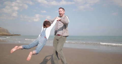 Father with daughter playing on the beach in spring Stock Video