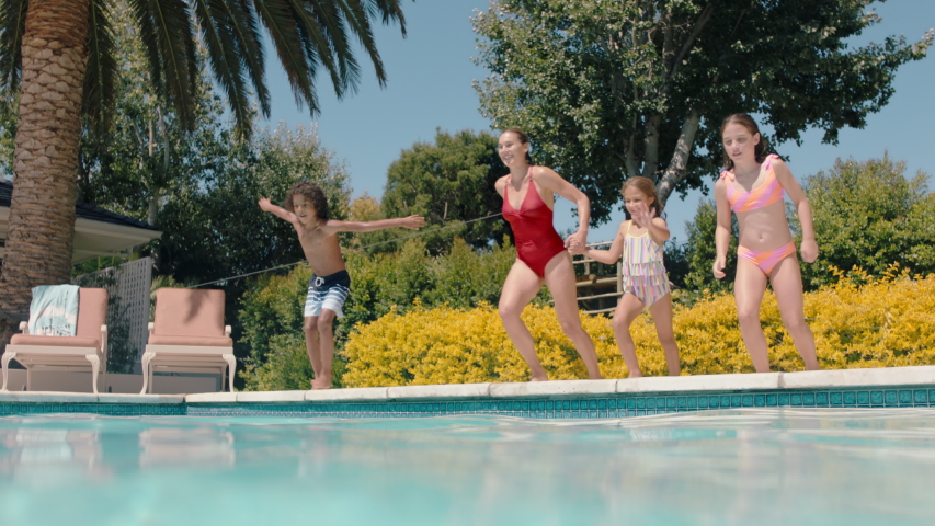 Mother with children jumping in swimming pool together happy family playfully enjoying summertime having fun splashing in cool water