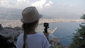 Child girl traveller with camera shooting video cityscape Alanya city, Turkey at viewpoint.