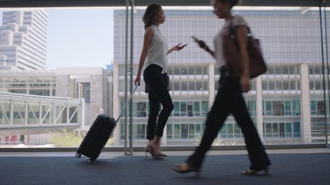 young business woman traveler walking using smartphone pulling trolly bag in airport texting checking messages female commuter traveling international for business trip 4k