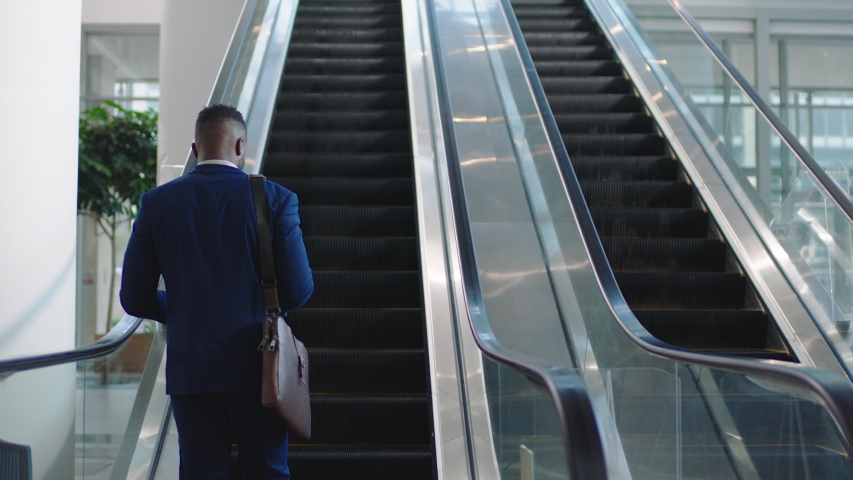 Young african american businessman using smartphone on escalator texting checking email messages online successful male executive arriving at work in corporate office building 4k | Shutterstock HD Video #1032464945