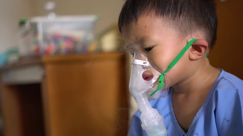 Sick Asian boy about 2 years and 8 months in hospital using inhaler containing medicine to stop coughing from disease like flu or RSV, Respiratory Syntactical Virus