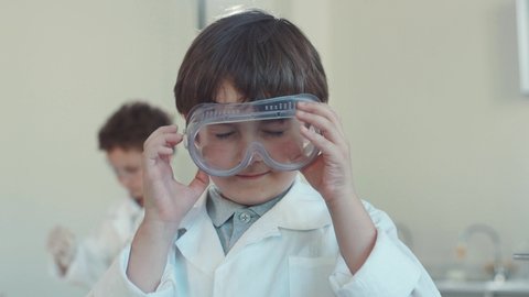 Adorable primary student child wearing protective glasses on head preparing for science experiments in a school laboratory.