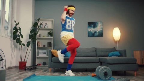 Crazy emotional funny athlete warming up and dancing to cool music on exercise mat in the living room.