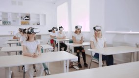 View of excited clever miscellaneous students with vr headsets watching online virtual lessons in a modern school. Concept of augmented reality and education. - Powered by Shutterstock - Get 15% off with code: PIKWIZARD15