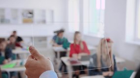 Close-up of a smart male teacher using a transparent future tablet in the classroom. Future technologies used in modern schools during the study process. - Powered by Shutterstock - Get 15% off with code: PIKWIZARD15