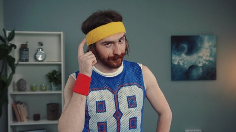 Portrait of tricky confident sportsman in retro clothes pointing at his brain. Close-up of handsome smart man mixing intelligence and body activity looking on camera indoors.