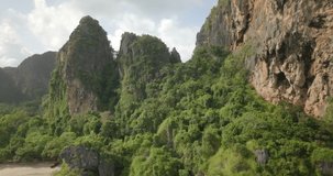Ascending aerial drone pull out view of natural karst limestone mountain formations and gulf of Thailand ocean in Railay, Krabi Province, Thailand
