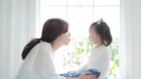 beautiful Asian mom and her cute daughter kissing with love while looking at each other