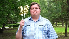 Big man holding golden balloons making the 18 number outdoor. 18th anniversary celebration party. - Powered by Shutterstock - Get 15% off with code: PIKWIZARD15