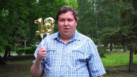Big man holding golden balloons making the 18 number outdoor. 18th anniversary celebration party. - Powered by Shutterstock - Get 15% off with code: PIKWIZARD15