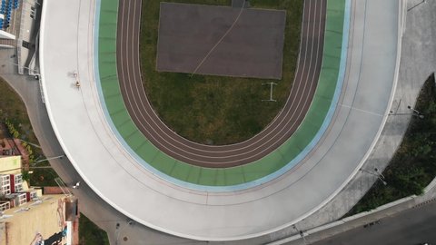 Professional track cyclists training at velodrome. Young strong men competing on cycling track. Workout training at velodrome. Drone view of velodrome