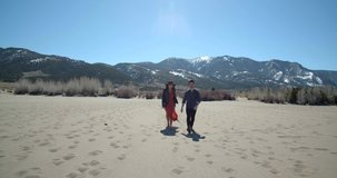 Couple Walking Through Great Sand Dunes & Mountains, Colorado