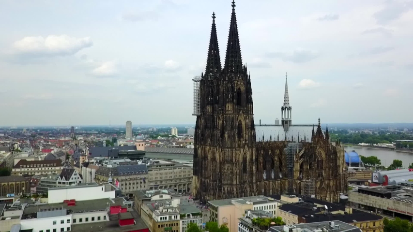 Aerial, reverse, drone shot, away from the German Cologne Cathedral, the Rein river and the Hohenzollern Bridge, in the background, on a sunny day, in Koln, Germany