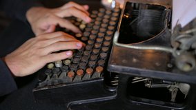 Close up of male hands typing on dusty, worn antique typewriter.