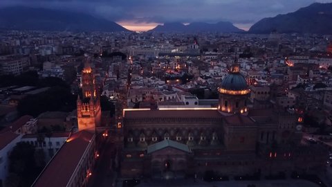 aerial side clip of Palermo Cathedral and downtown in a cloudy evening with beautiful night lights, Sicily, Italy. Built in arab-norman style, it is a UNESCO World Heritage Site