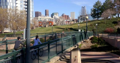 Denver, Colorado / USA - April 11 2019: Riding Bike Through Denver Park, Drone Shot of City Skyline