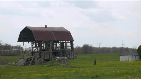 An old falling apart barn on a farmers field with birds swooping in and out of it