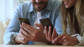 Young couple using two smartphones talk laugh, man and woman customers holding phones in hands shopping in app checking social media, mobile technology lifestyle and addiction concept, close up view