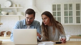Serious young couple husband and wife pay bills online on website app doing paperwork planning budget discuss finances calculate mortgage payments using laptop computer sit at kitchen table at home - Powered by Shutterstock - Get 15% off with code: PIKWIZARD15