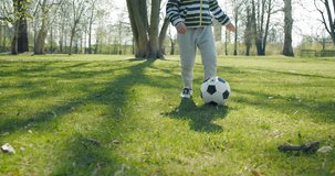 Child  plays soccer  on the  grass, summer sunny day under sunlight. 4K slow motion video
