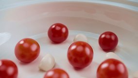 Tomato sauce is poured into a white plate with red cherry and garlic. 4K slow motion video