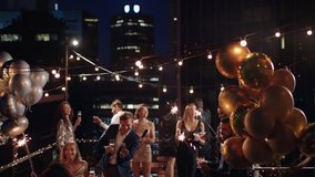 friends celebrating new years eve party dancing throwing confetti enjoying glamorous celebration wearing stylish fashion at formal social gathering on rooftop at night 4k - Powered by Shutterstock - Get 15% off with code: PIKWIZARD15