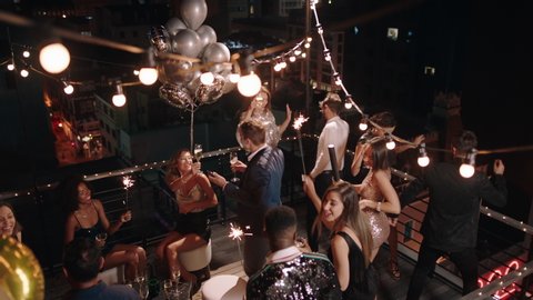 top view friends celebrating new years eve party dancing throwing confetti enjoying glamorous celebration wearing stylish fashion social gathering on rooftop at night 4k